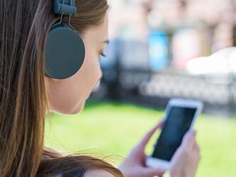 teenage girl wearing headphones looking at a smartphone